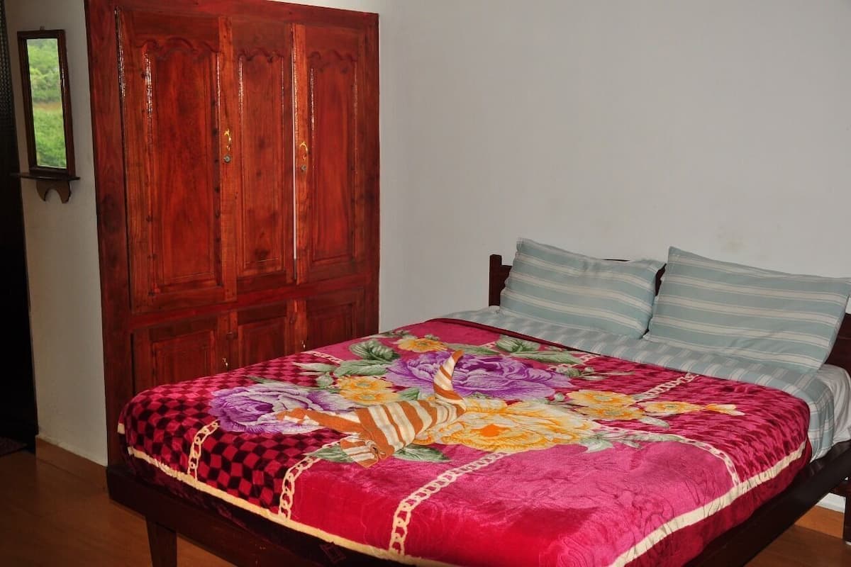 Una cama con colcha estampada, un armario de madera y una pared lisa.