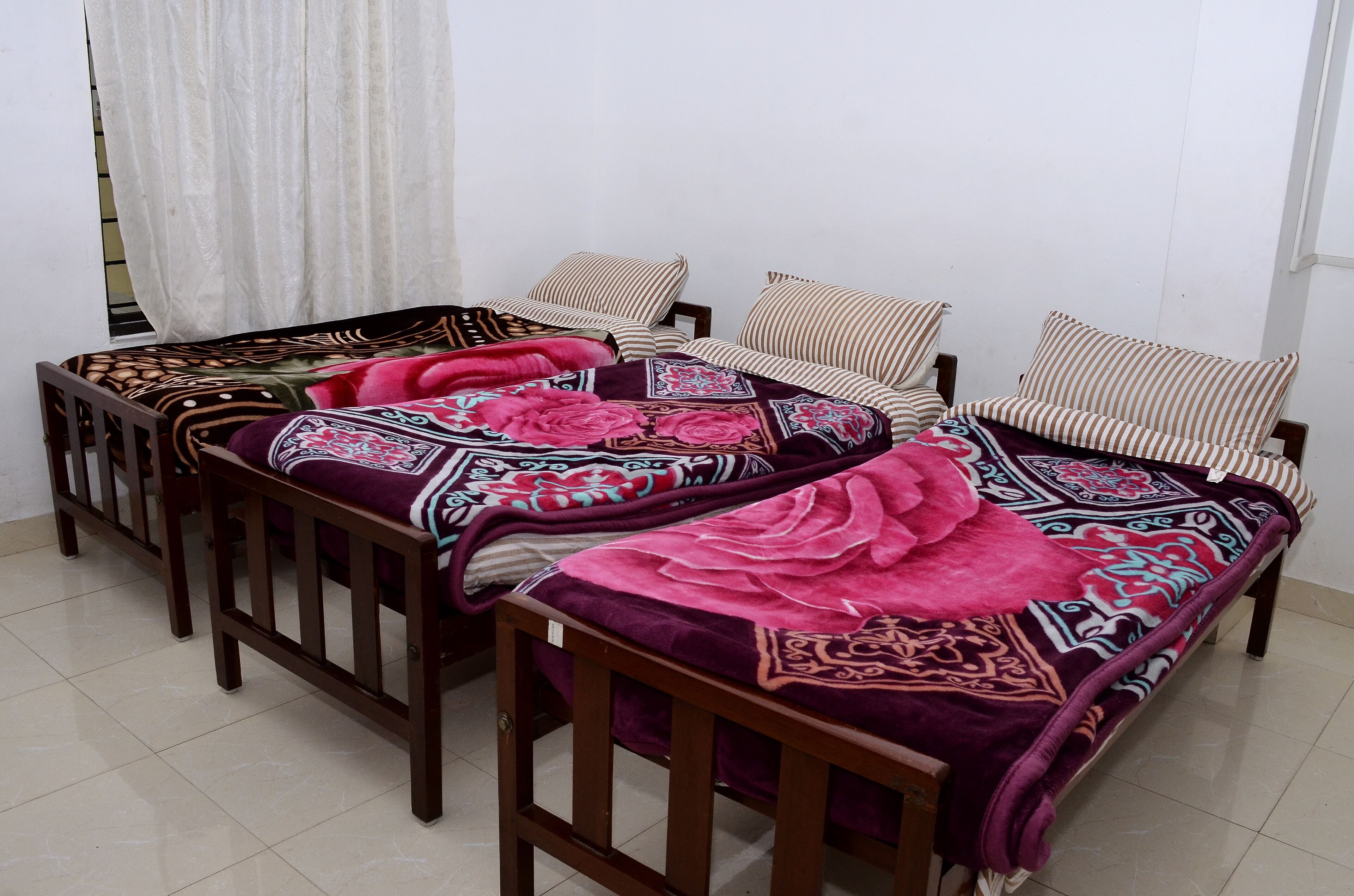 Una habitación con dos camas de madera, cada una con una colcha y cojines estampados.