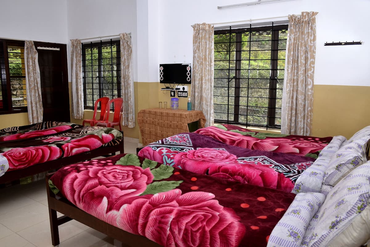 Una habitación con dos camas, cada una con ropa de cama floral, una mesita con un espejo y ventanas con cortinas.