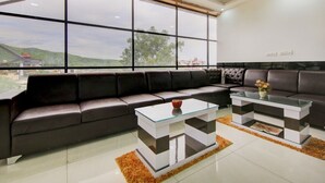 Un salon moderne doté d’une grande fenêtre, d’un canapé et de deux tables basses au plateau en verre.