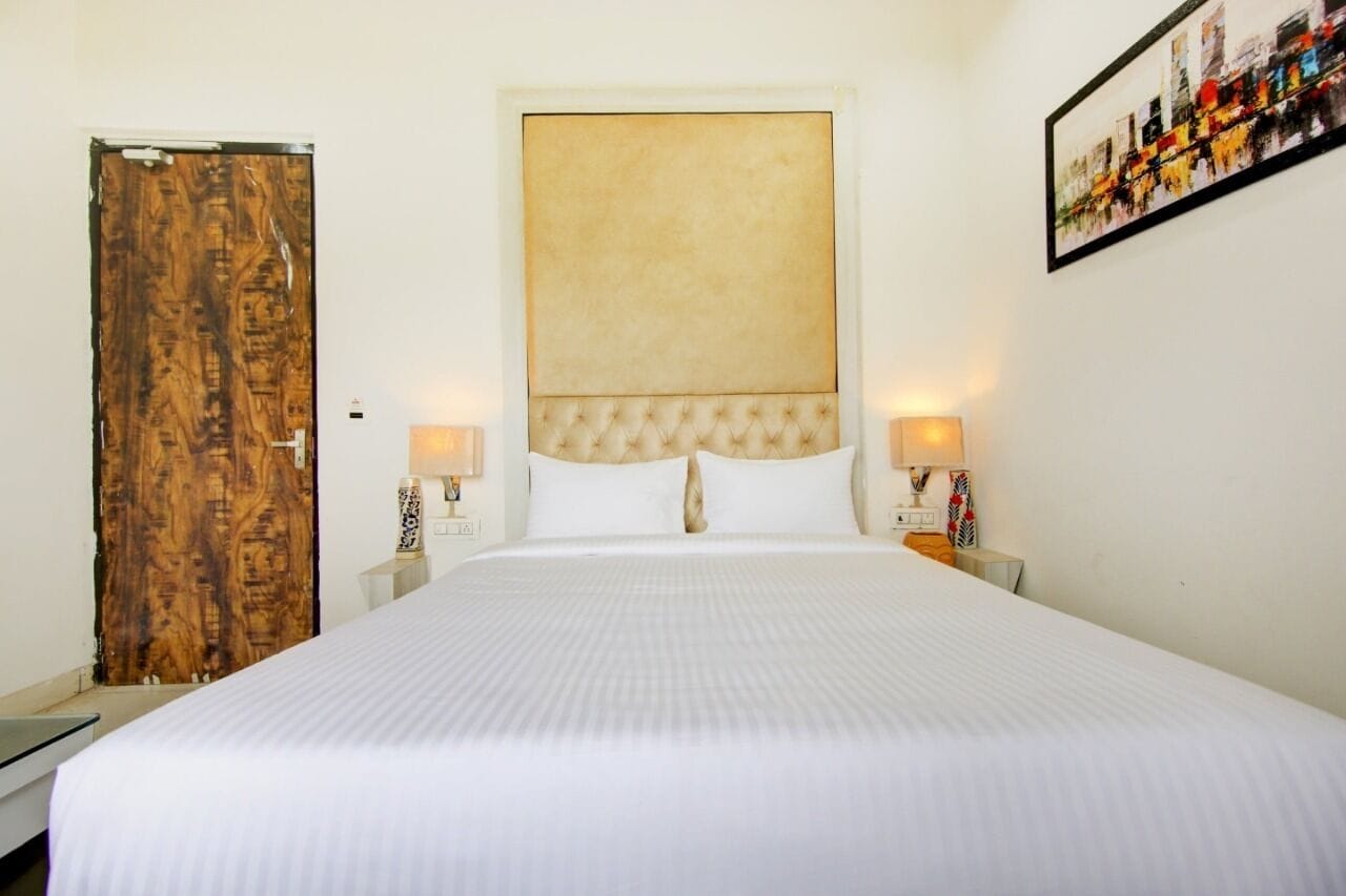 Une chambre d’hôtel avec un grand lit, une porte en bois et un tableau encadré au mur.