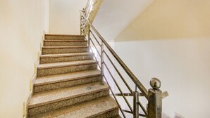 Un escalier avec des marches en granit et une rampe métallique.