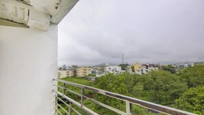 Un balcon doté d’une rambarde en métal, donnant sur un quartier résidentiel avec des arbres et des immeubles.