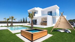 Ein modernes, weißes Haus mit Swimmingpool, Whirlpool und Zelt.
