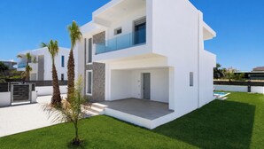 Una casa moderna de dos pisos con techo plano, ventanas amplias y un balcón.