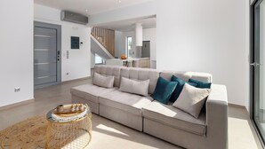 Ein modernes Wohnzimmer mit einem beigefarbenen Sofa, einem Couchtisch und einer Treppe, die in eine obere Ebene führt.