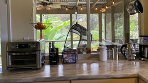 A kitchen with a large window, a ceiling fan, hanging pots, and a coffee maker.