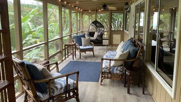 A covered porch with wicker furniture, large windows, and ceiling fans.