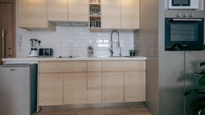 A modern kitchen with wooden cabinets, a Bosch microwave, and a compact refrigerator. - NAIRO STUDIOS (Nairobi)