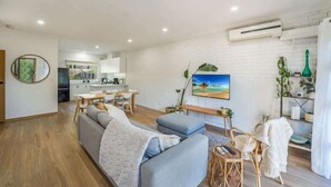 A modern living room with a sofa, a dining area, and a kitchen in the background. - Cozy Newtown 2 bedroom unit (Newtown)