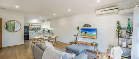 Un salon moderne avec un canapé, un coin repas et une cuisine en arrière-plan.