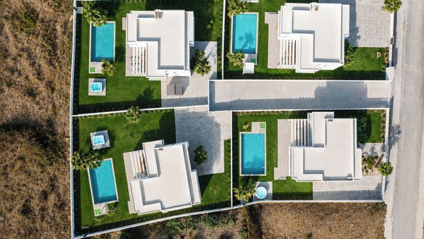 A residential property with multiple swimming pools, each with a separate deck area, surrounded by well-maintained lawns and a few trees. - Martini Villas - Rosemary in Kremasti (Κρεμαστή)