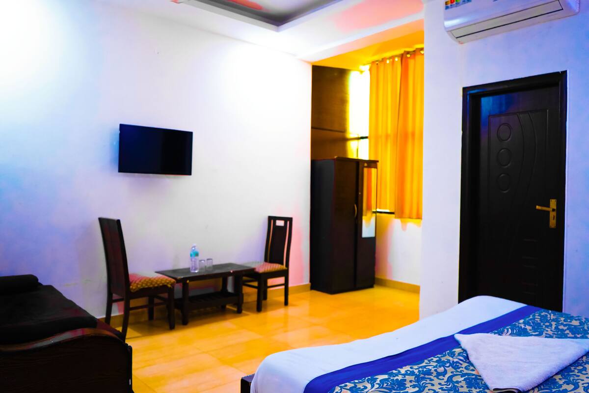 Une chambre d’hôtel comprenant un lit, un bureau, deux chaises, une télévision et une armoire.