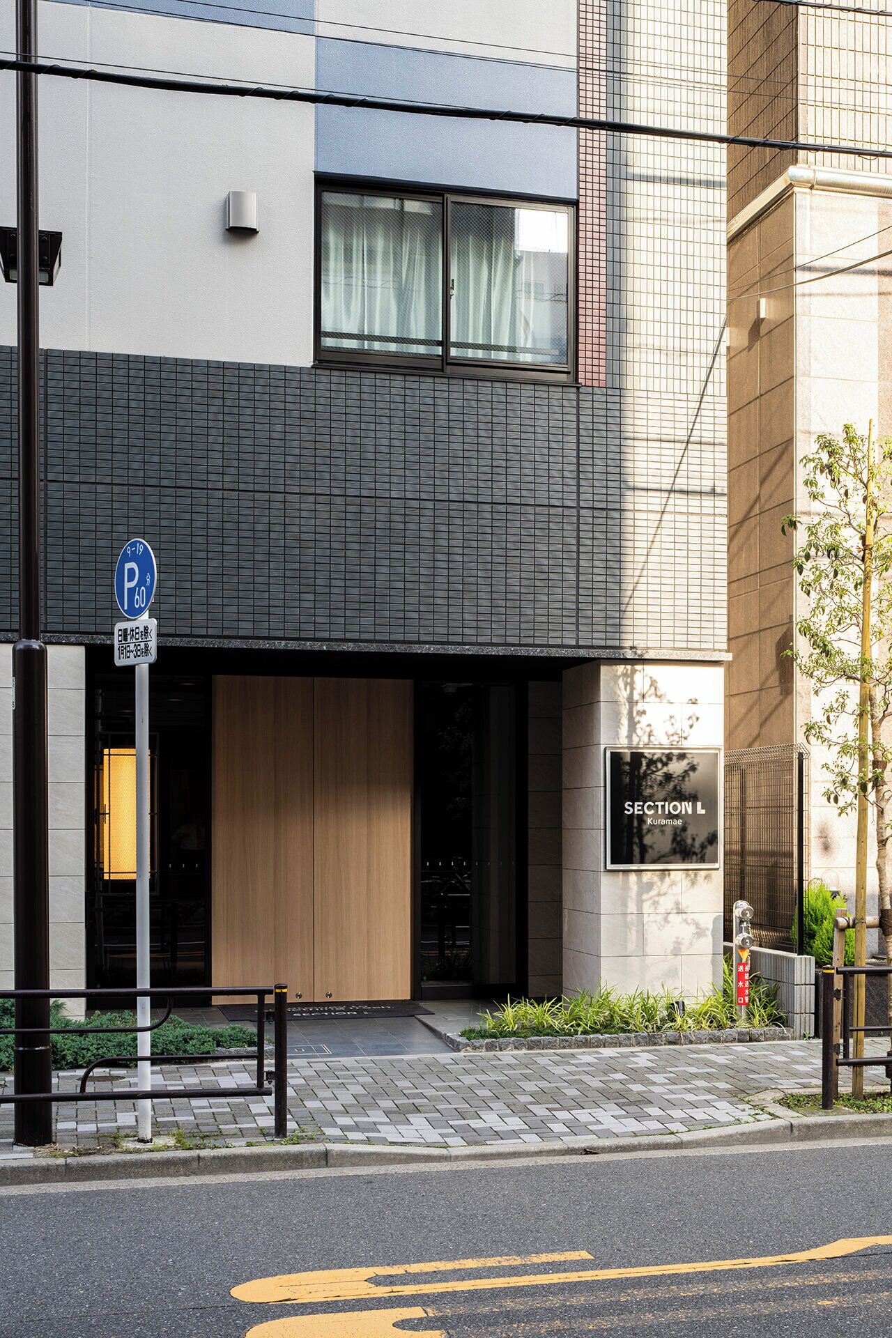 A modern building with a parking sign, a section label sign, and a gated entrance.