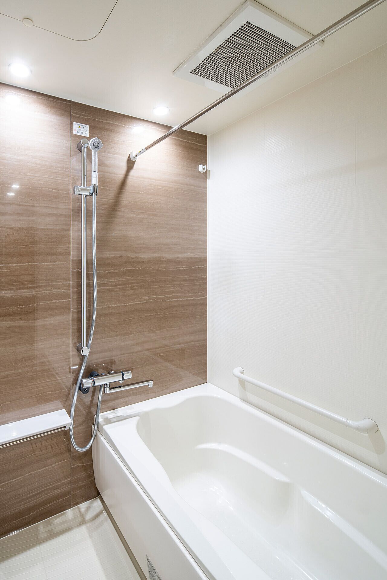 Une salle de bain moderne équipée d’une baignoire, d’une douche avec un pommeau de douche amovible et d’un panneau de commande fixé au mur.