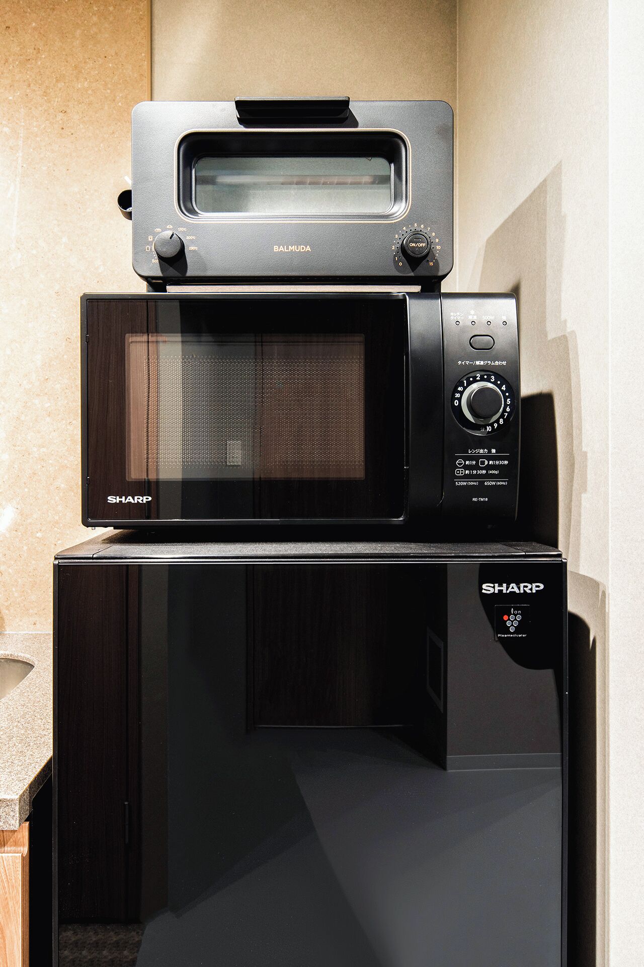 A stacked microwave oven with a toaster on top.