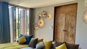 A modern living room with a sectional sofa, a round coffee table, and a decorative wall piece. - La Maison d'Ulysse  (Kerobokan)