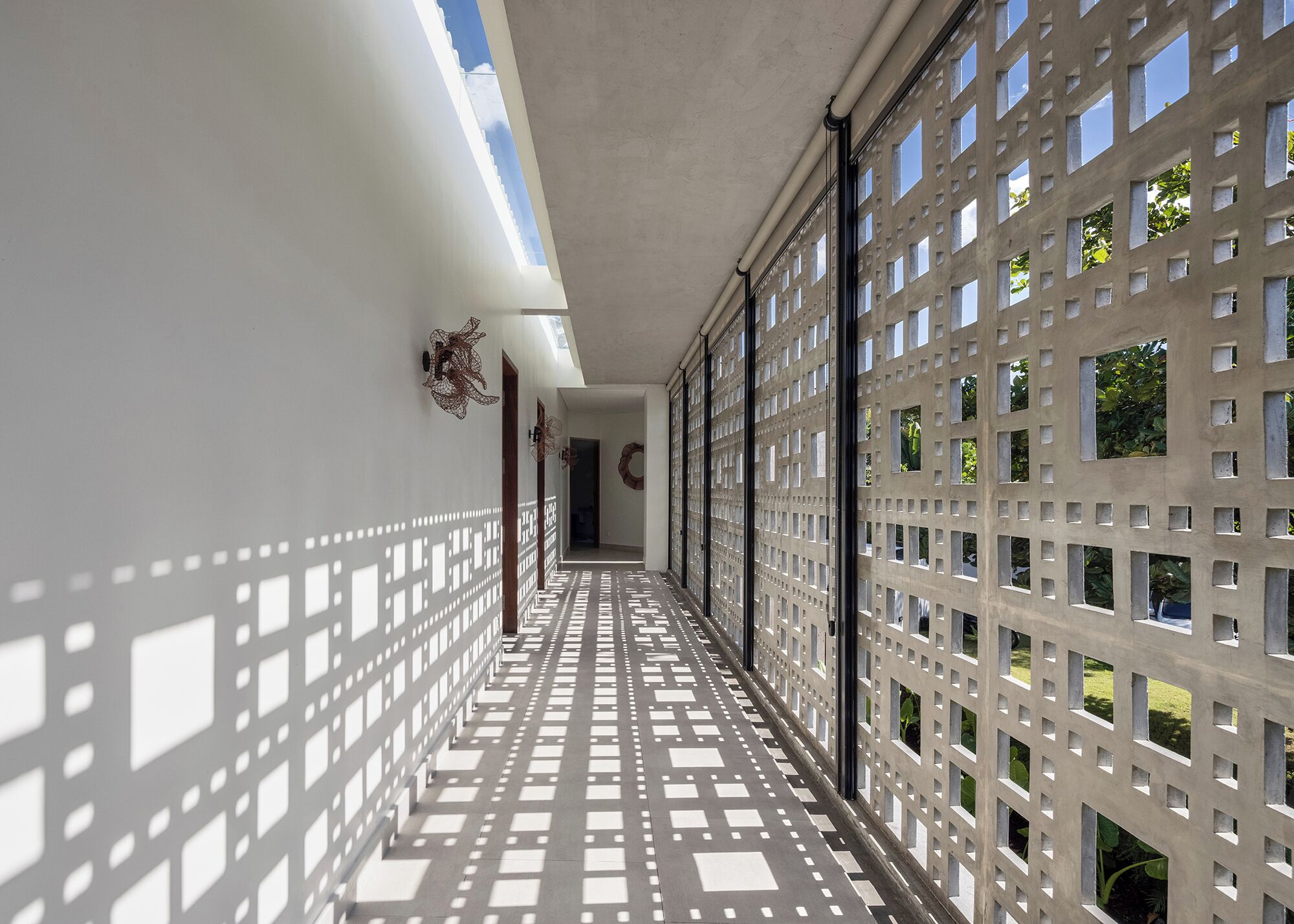 A corridor with a patterned floor, a ceiling with a skylight, and a wall with a grid of windows.