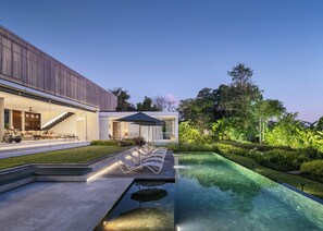 A modern house with a swimming pool, outdoor seating, and a well-maintained garden.