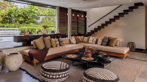 A modern living room with a large L-shaped sectional sofa, a coffee table, and a staircase. - La Maison d'Ulysse  (Kerobokan)