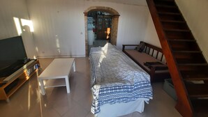 Un salon avec un canapé, un téléviseur, une table basse et un escalier.