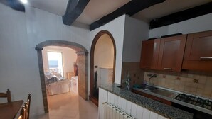 Une cuisine avec des meubles en bois, un plan de travail en granit et un pare-feu en carrelage. Il y a un radiateur sous l’évier et une fenêtre donnant sur l’extérieur.