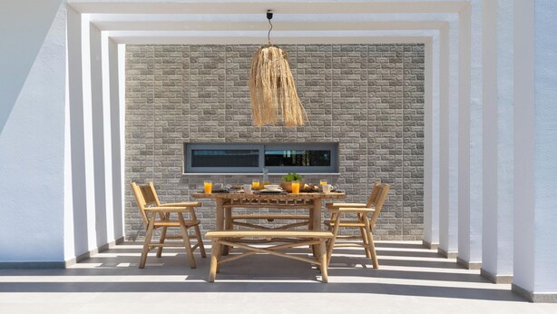 Un coin repas avec un mur en briques en arrière-plan, un luminaire suspendu et une table dressée pour le petit-déjeuner.