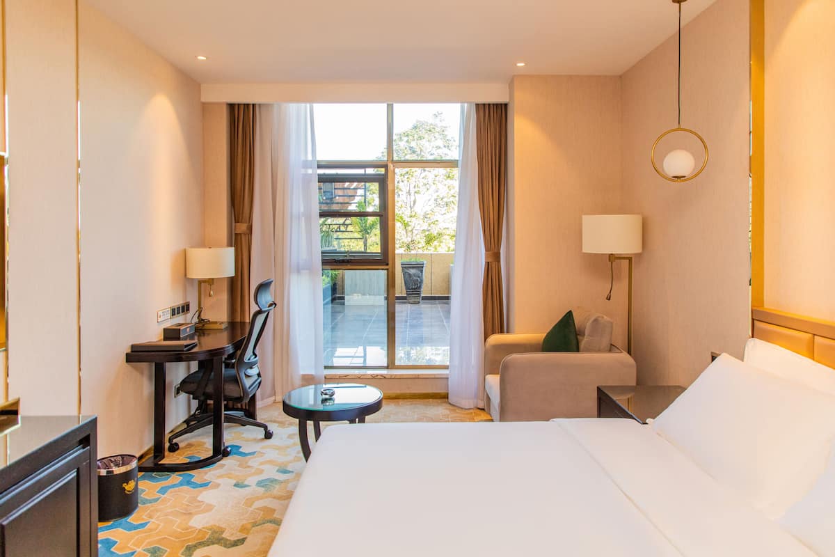 A hotel room with a bed, a desk, a chair, a small table, and a sofa.