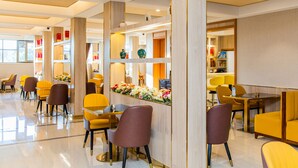 A modern hotel lobby with yellow and brown chairs, a reception desk, and a floral arrangement. - The Venetian Hotel   (Lusaka)