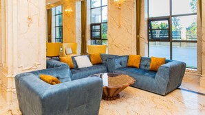A modern lobby with a sectional sofa, a coffee table, and a large window offering a view of the outdoors. - The Venetian Hotel   (Lusaka)