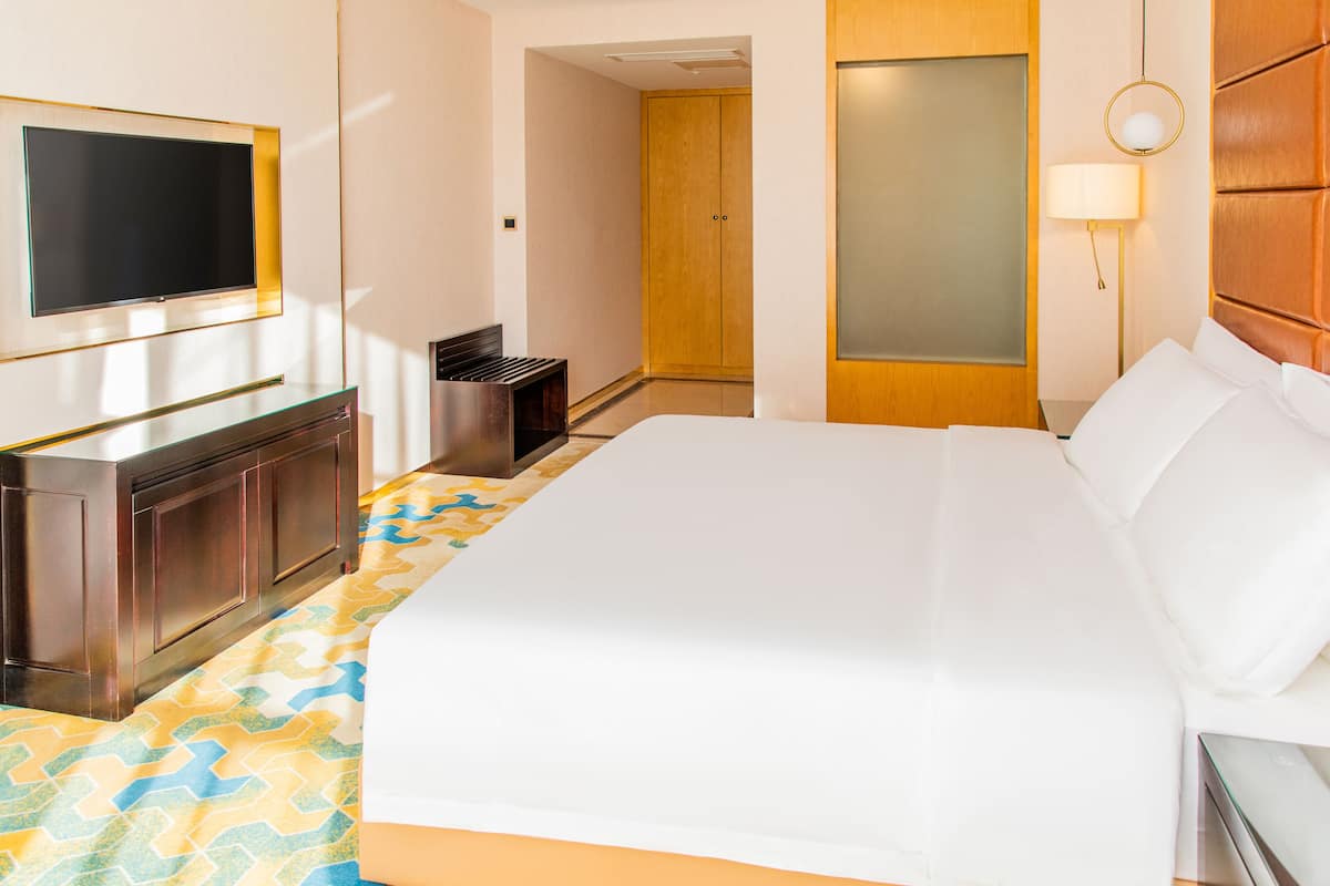 A hotel room with a bed, a TV, a desk, and a wardrobe.