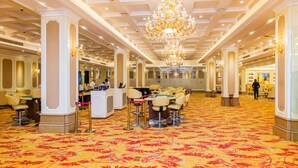 A spacious hotel lobby with a large chandelier, multiple seating areas, and a reception desk. - The Venetian Hotel   (Lusaka)