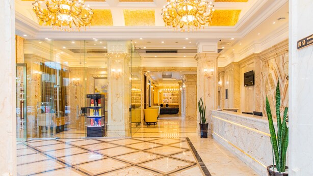 A hotel lobby with a marble floor, a reception desk, and a chandelier. - The Venetian Hotel   (Lusaka)