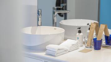A bathroom with a large white sink, a mirror, a towel rack, and a glass of water.