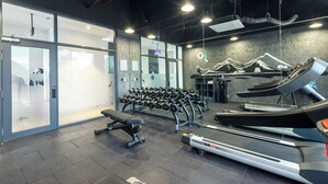 A gym with treadmills, dumbbells, and a bench.