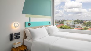 Een hotelkamer met twee bedden, uitzicht op de stad en een modern wandontwerp.