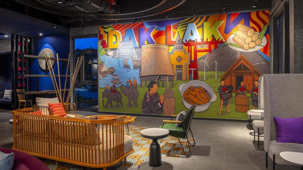 A cozy lounge area with a colorful mural, a wooden crib, and a seating area with a purple cushion.