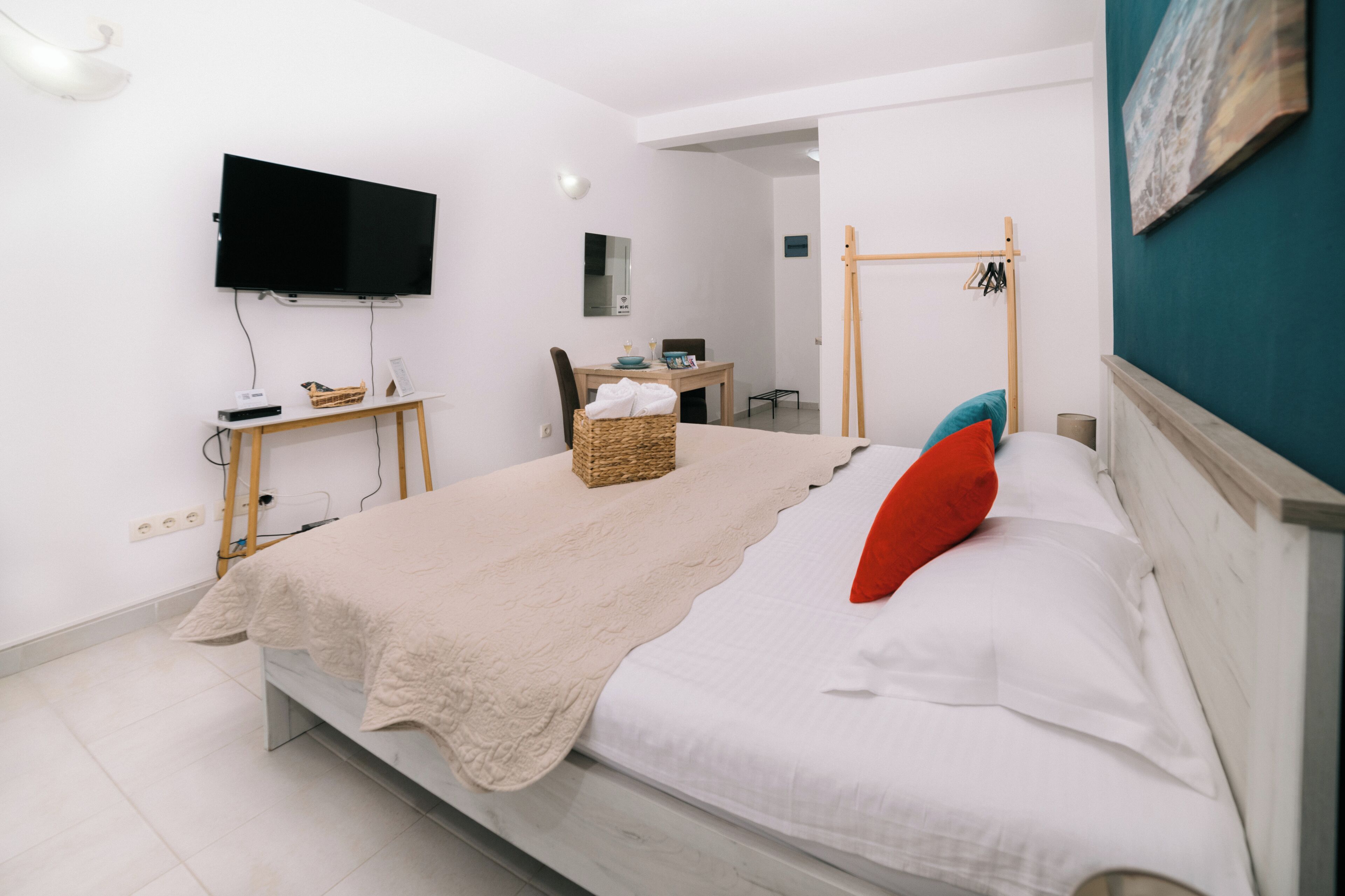Quarto com uma cama, televisão na parede, escrivaninha e uma cadeira.