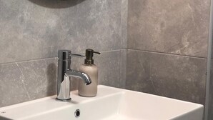 Une salle de bain avec un lavabo blanc, un robinet chromé et un distributeur de savon.
