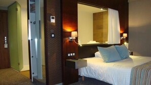 A hotel room with a bed, bedside lamps, a mirror, and a green door. - Alysson Hôtel (Oloron-Sainte-Marie)