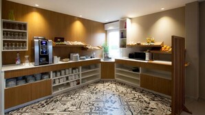 A modern hotel room with a kitchenette, built-in shelves, and a patterned floor. - Alysson Hôtel (Oloron-Sainte-Marie)