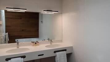 A modern bathroom with two sinks, a large mirror, and a wooden accent wall.