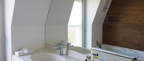 Een moderne badkamer met twee wasbakken, een grote spiegel en een wand van hout.