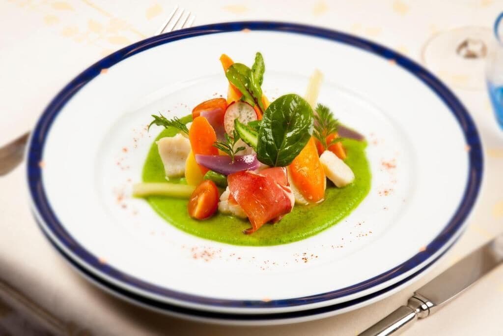 A plate of food with various vegetables and a green sauce.