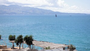 A coastal scene with a clear view of the sea, a sailboat, and distant mountains. - Harmony Hotel (Sarandë)