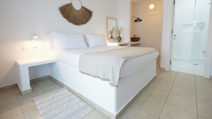 A bedroom with a bed, bedside tables, a wall-mounted fan, a mirror, and a door leading to another room. - Harmony Hotel (Sarandë)
