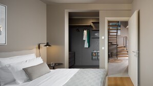 A bedroom with a bed, bedside table, lamp, and a view into a hallway leading to a bathroom and a staircase. - Modern apartment with hot tub (Poreč)