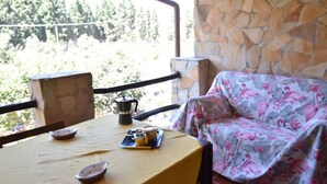 Una mesa con una bandeja de té y tazas, un sofá floral y una pared de piedra.