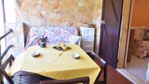Un comedor con pared de piedra, mantel amarillo y camino de mesa floral.