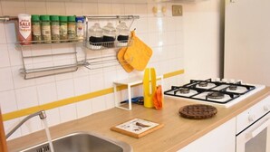 Una cocina con estufa a gas, un fregadero, un especiero y una toalla amarilla.